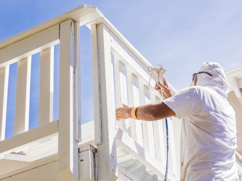 House Painter Spray Painting A Deck of A Home